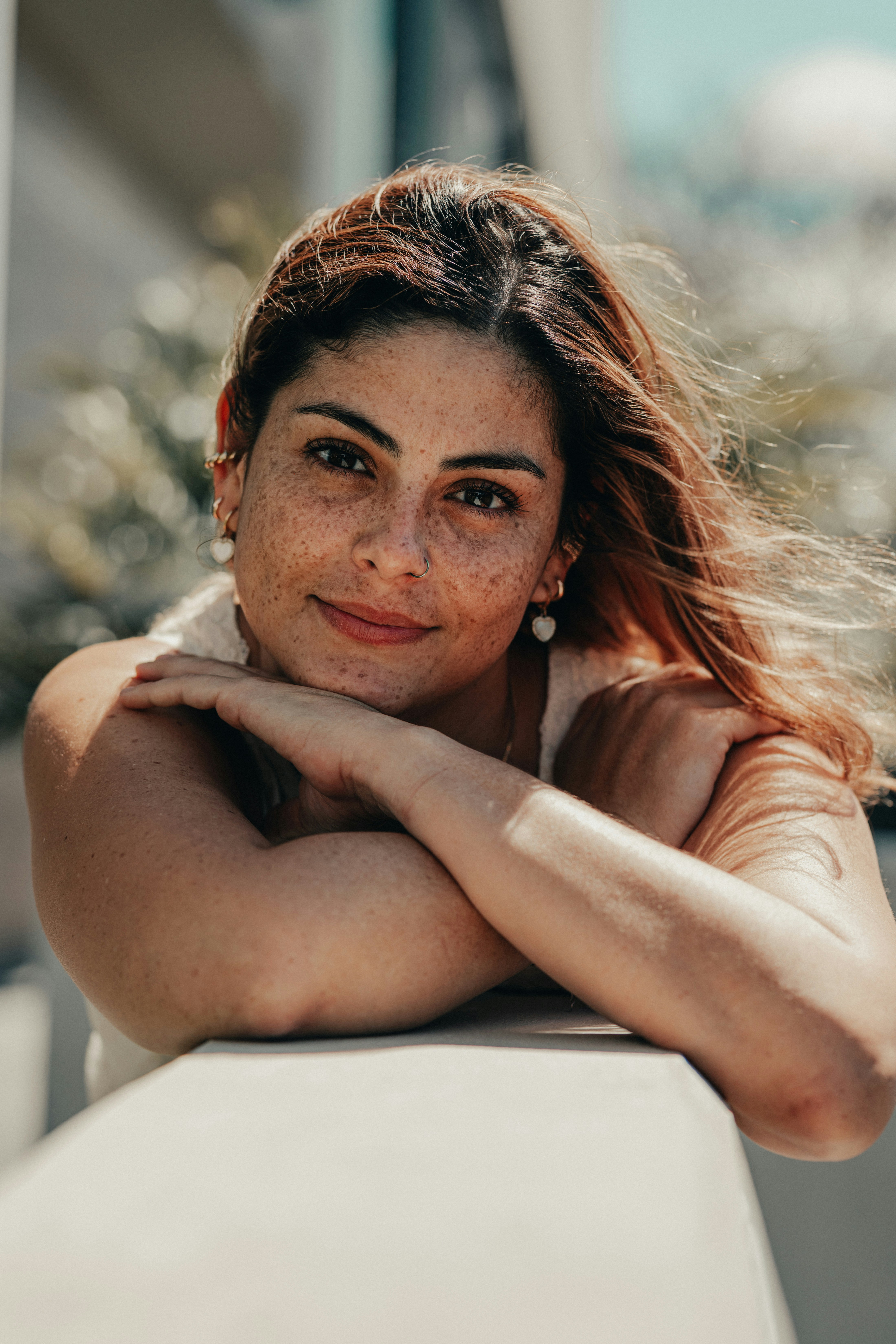A young adult resting her chin on her arms and looking thoughtfully toward the camera