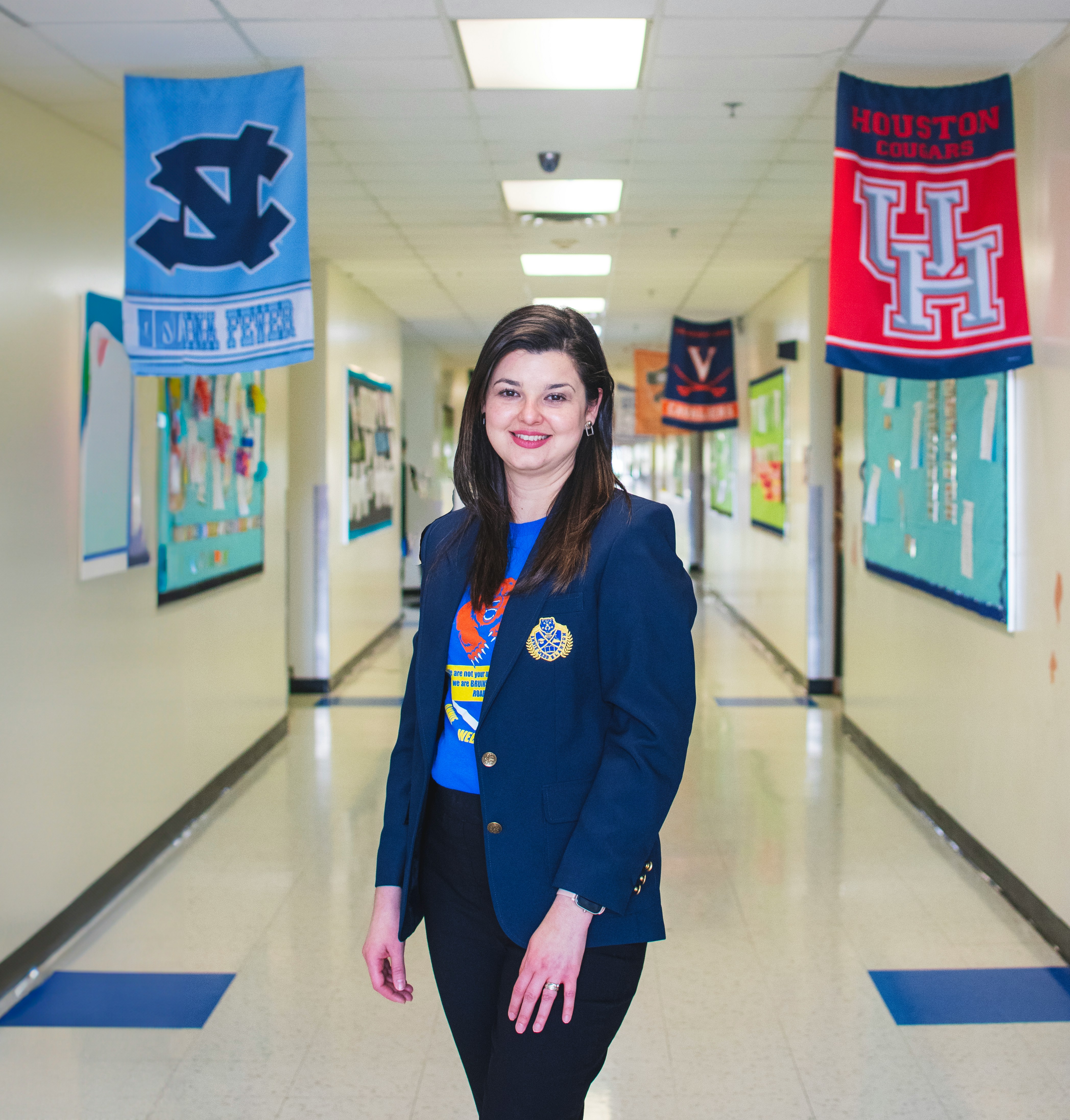 A school representative standing in a school hallway decorated with college banners